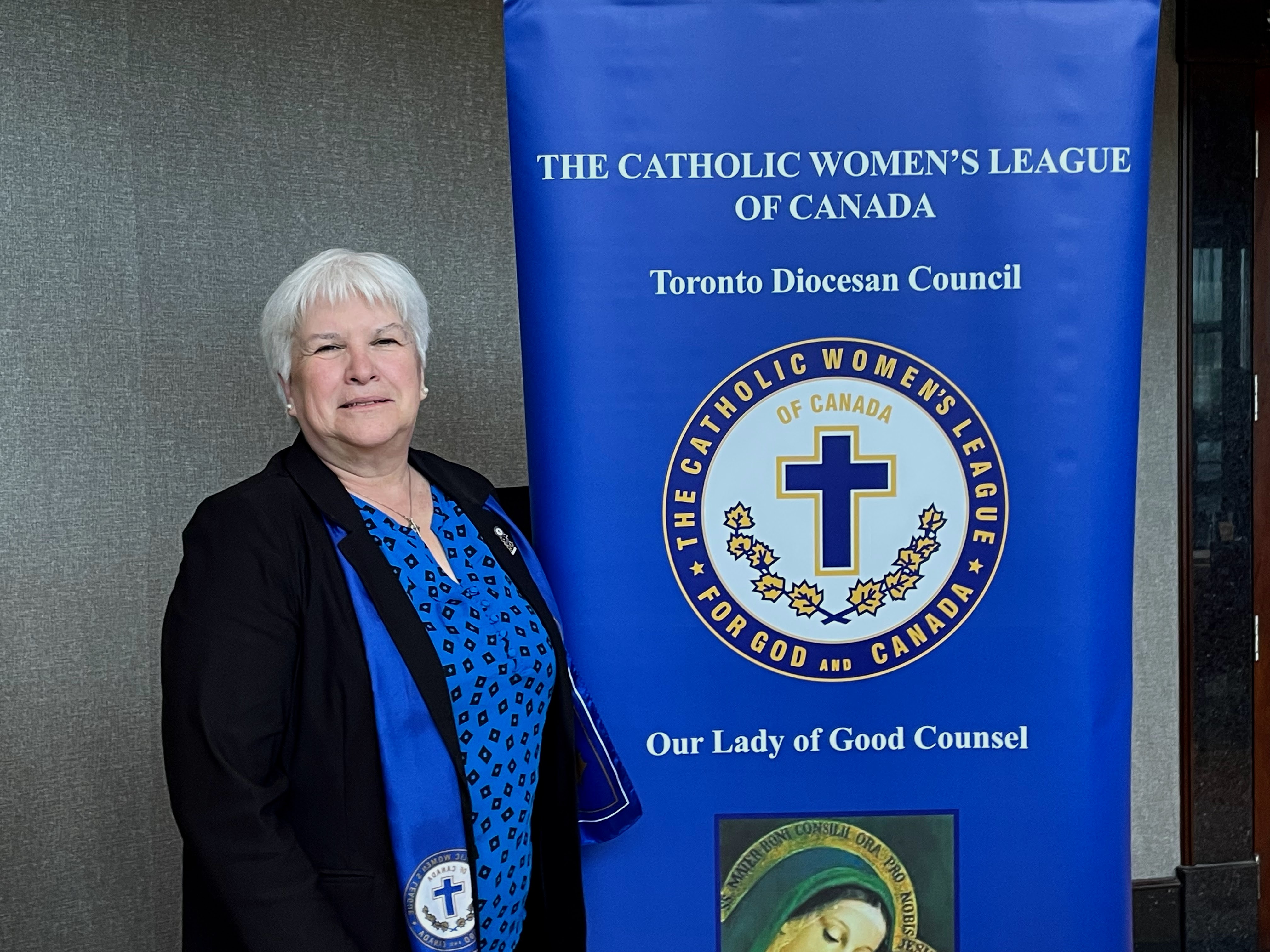 Toronto Diocesan CWL president standing beside CWL banner