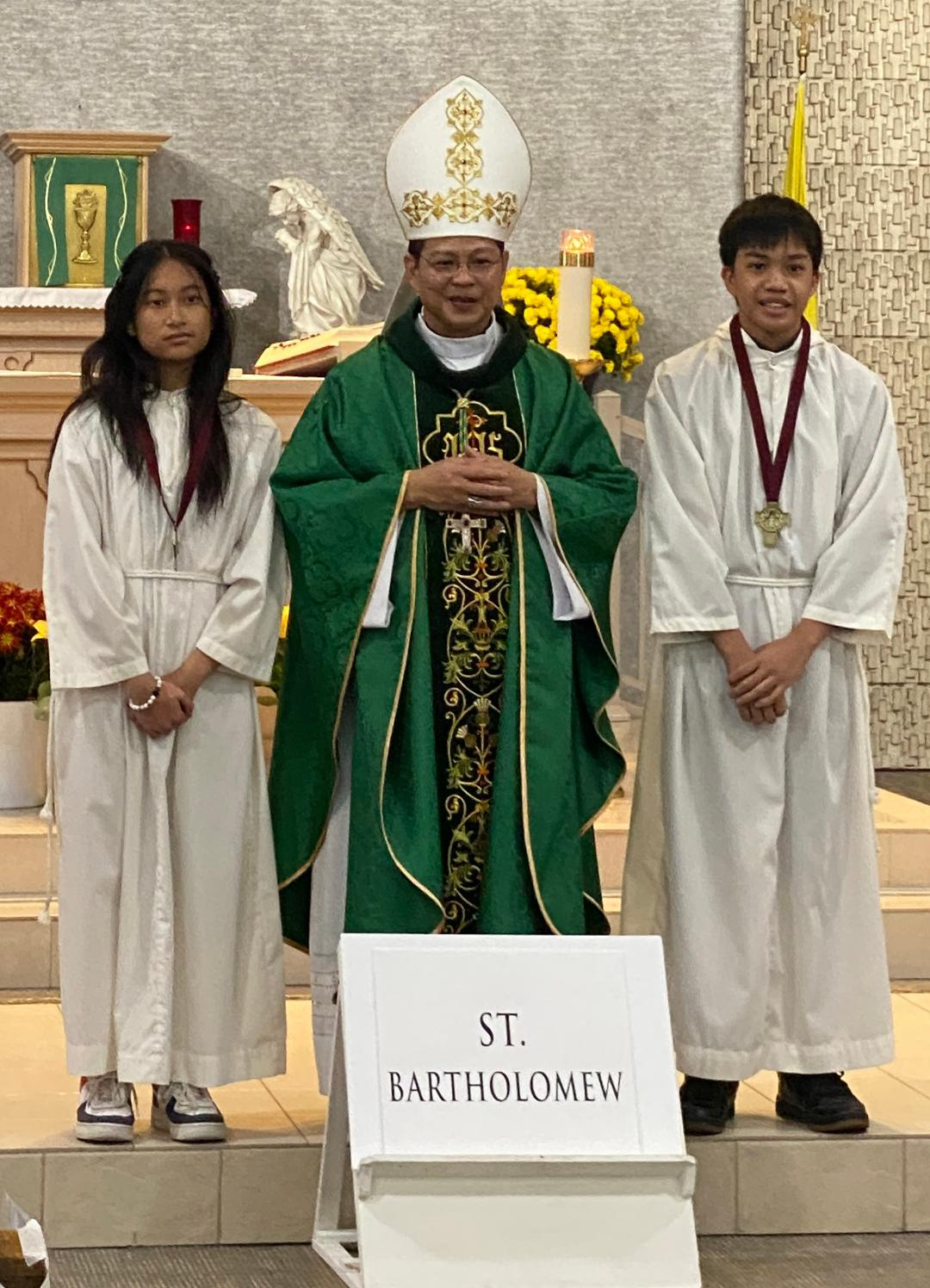 Two altar severs stand with Bishop Nguyen